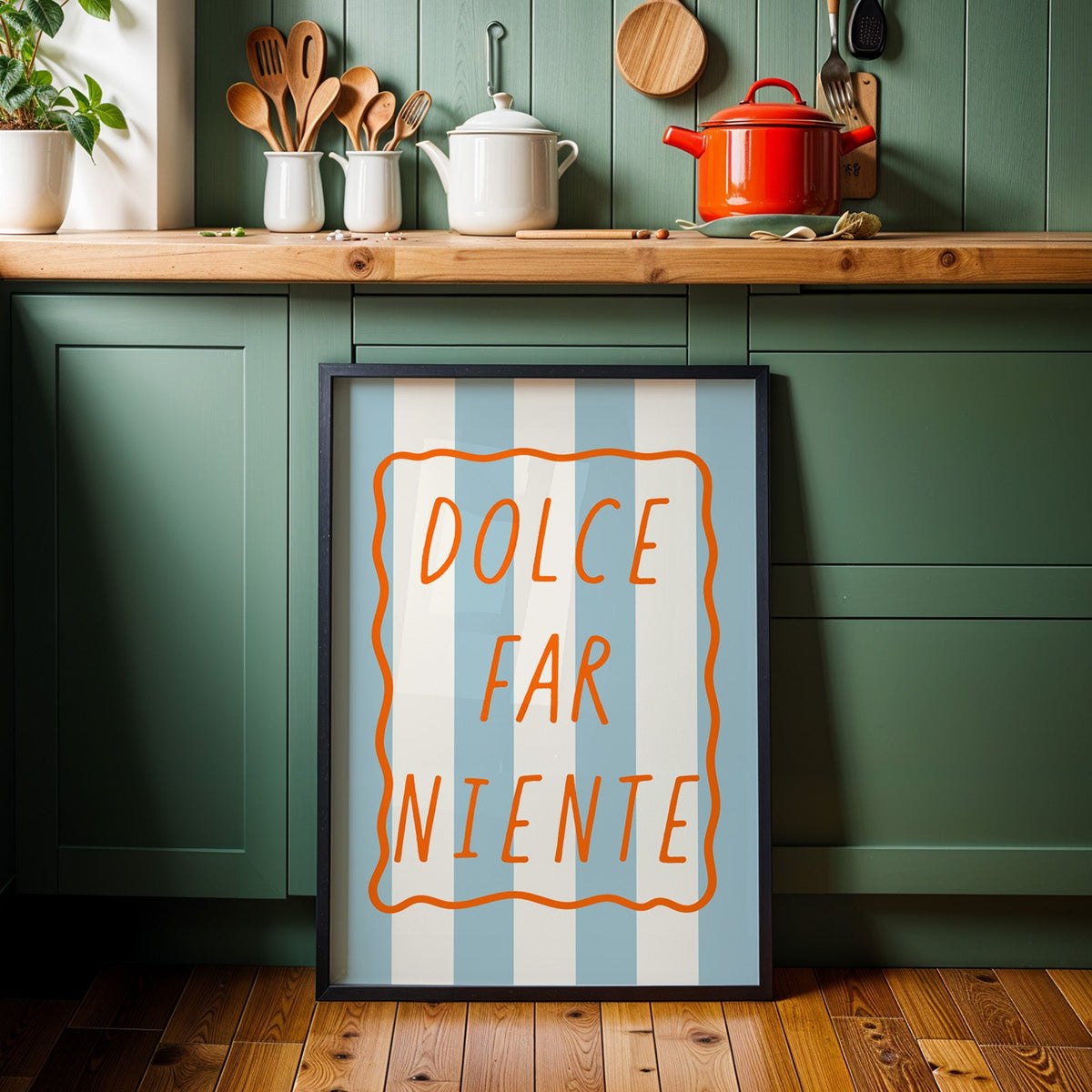 Dolce far niente print in a black frame against sage green kitchen cabinets