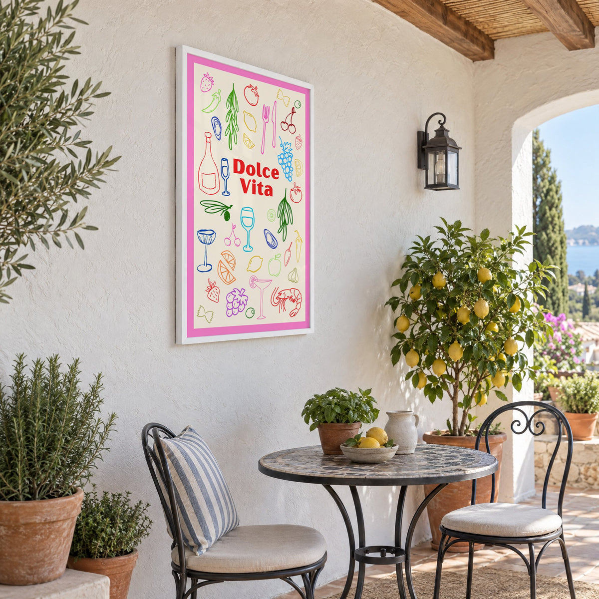 Dolce Vita colorful food doodle print in a white frame on a sunny patio wall beside a potted lemon tree
