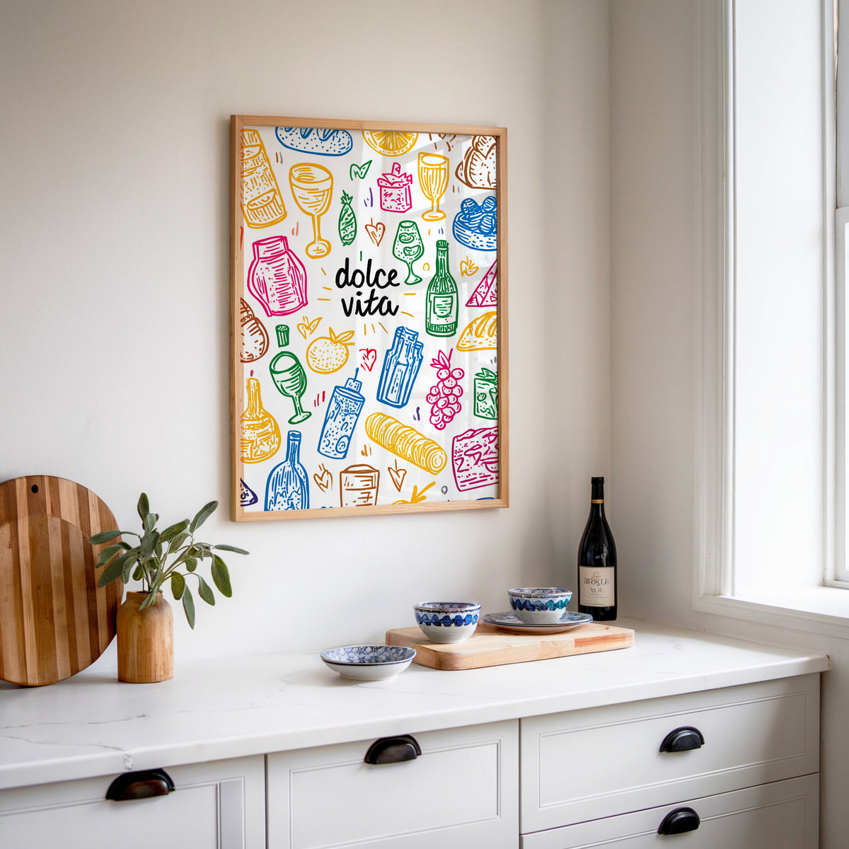 Dolce Vita doodle print in an oak frame above a white sideboard with a bottle of wine