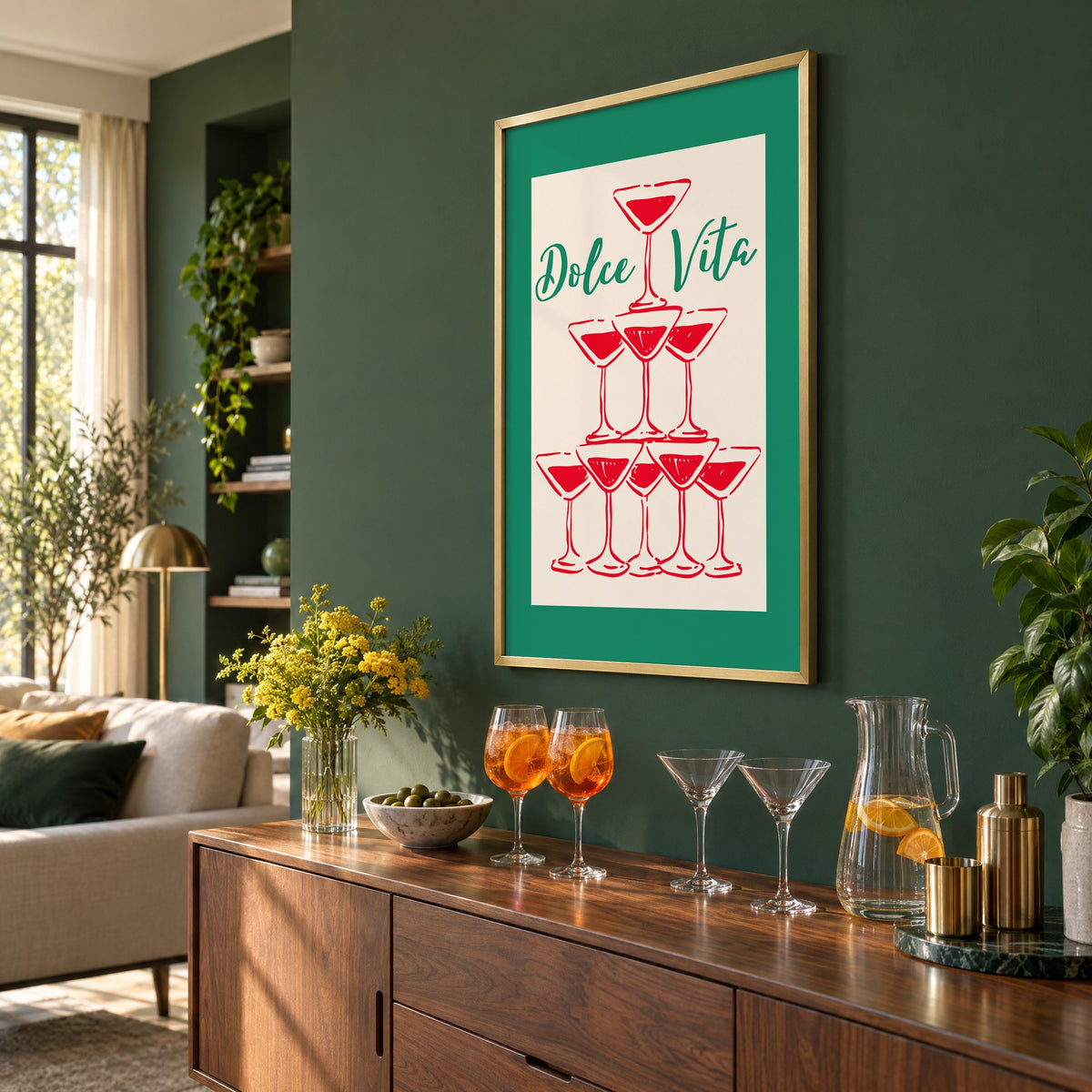 Dolce Vita red martini tower print in a brass frame on a bottle green wall above a sideboard with spritz and martini glasses, seen at an angle