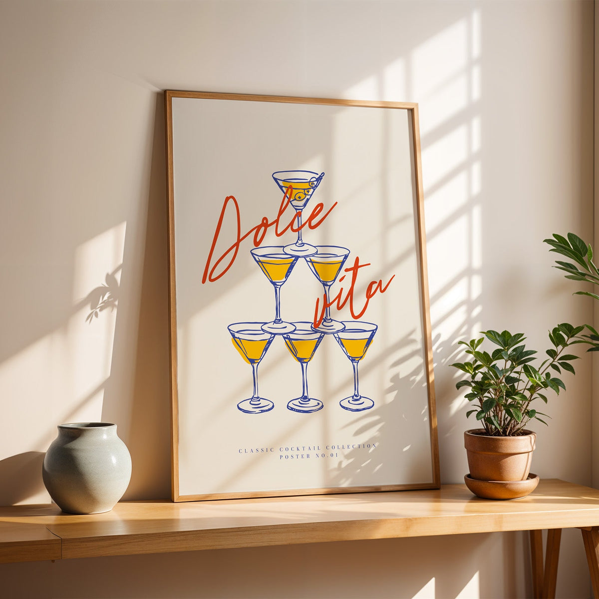Red script martini poster in a slim oak frame on a sunlit wood console with a stoneware vase