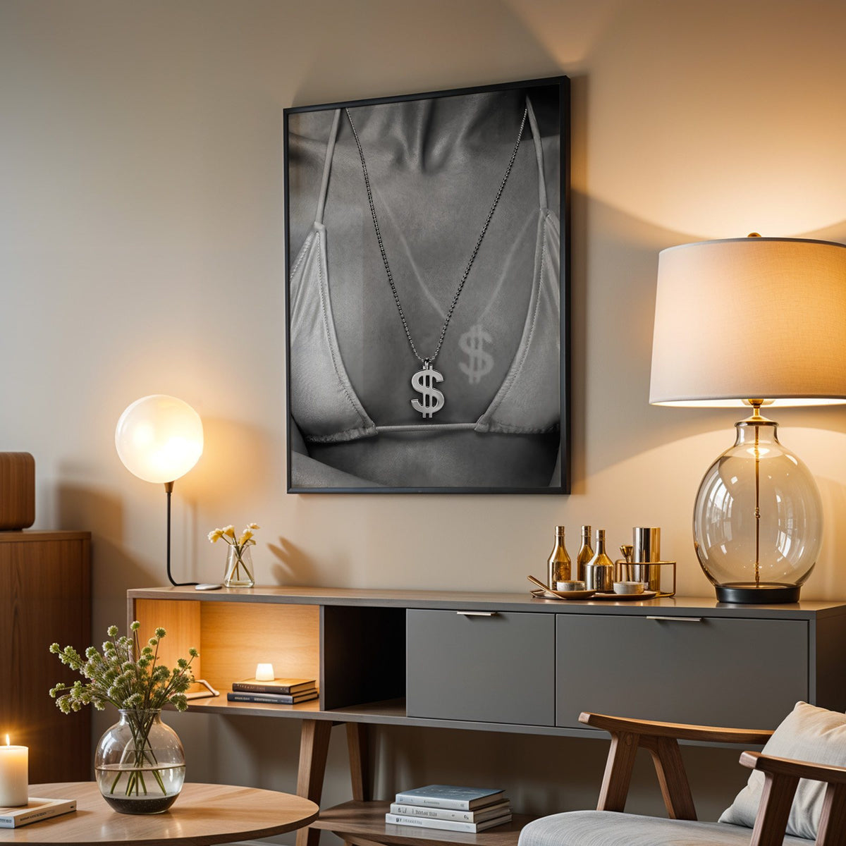 Dollar sign pendant and tan line close-up print in a black frame above a grey media console with a glass table lamp