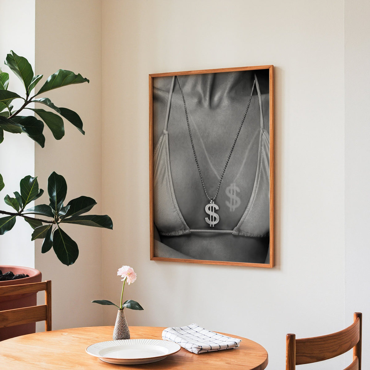 Dollar sign pendant and tan line close-up print in a teak frame above a round wooden dining table