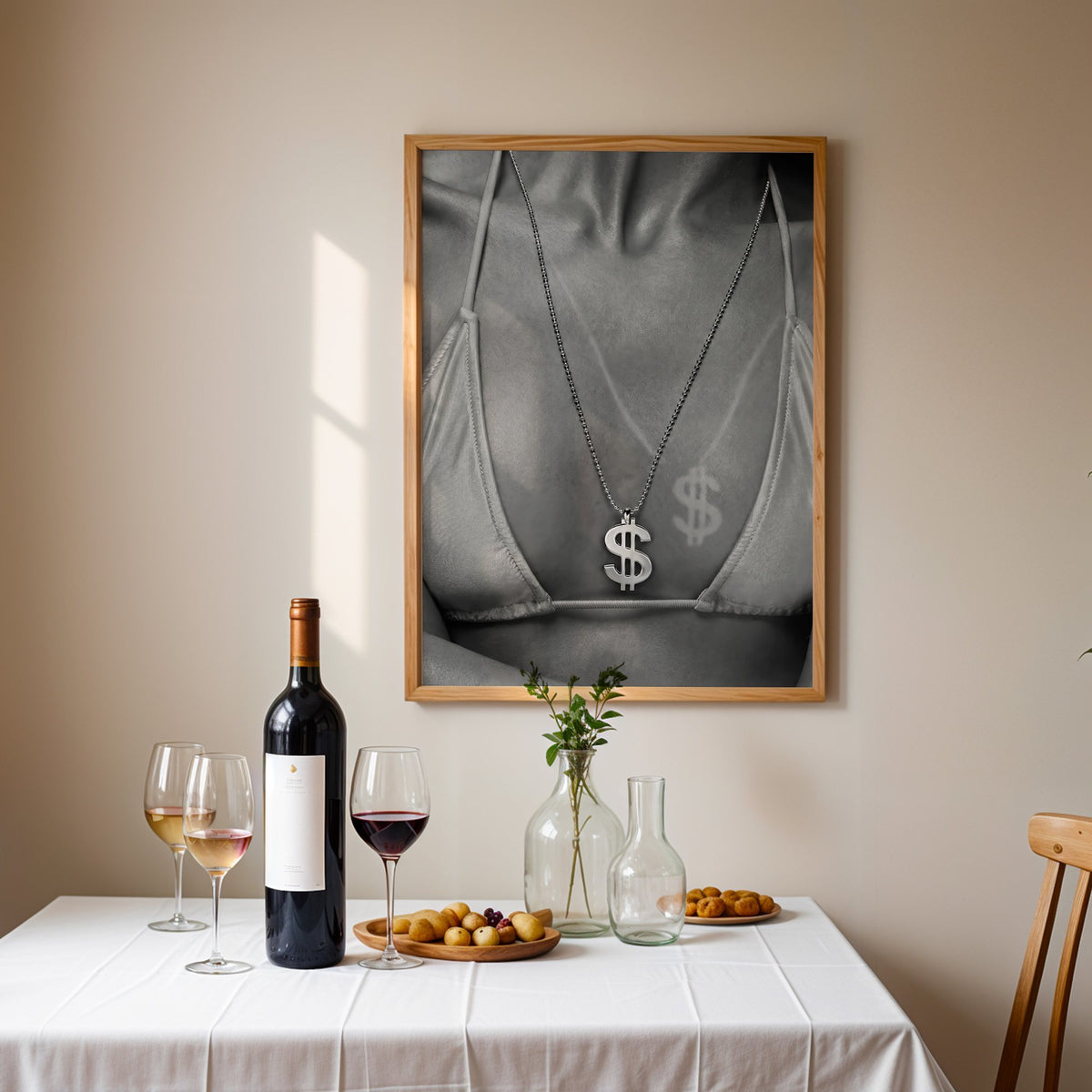 Dollar sign pendant and tan line close-up print in an oak frame above a table set with red wine and glasses