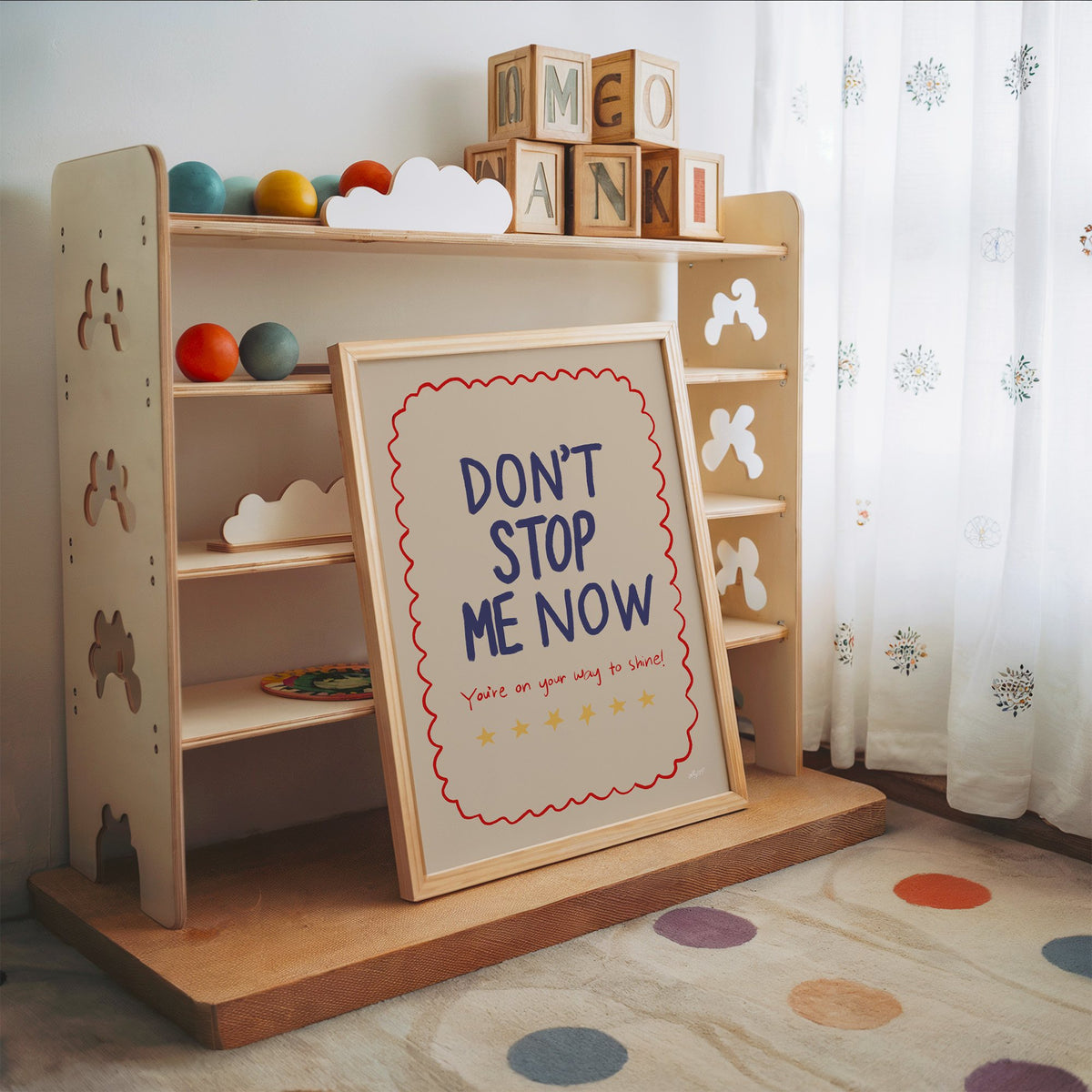 Dont stop me now star lettering nursery print in an oak frame leaning on a toy shelf with wooden letter blocks