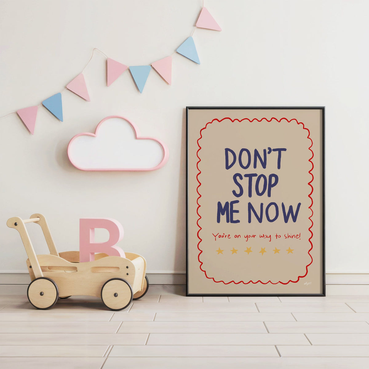 Dont stop me now star lettering nursery print in a black frame under pastel bunting by a wooden baby walker