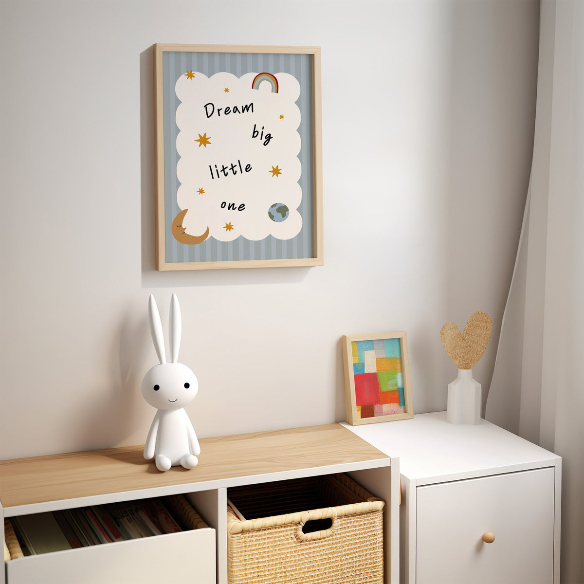 Dream big little one rainbow nursery print in an oak frame above a kids cubby shelf with a woven basket and bunny lamp