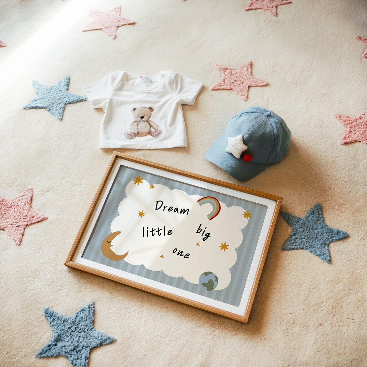 Landscape dream big little one rainbow nursery print in a matted oak frame on a star rug with a baby tee