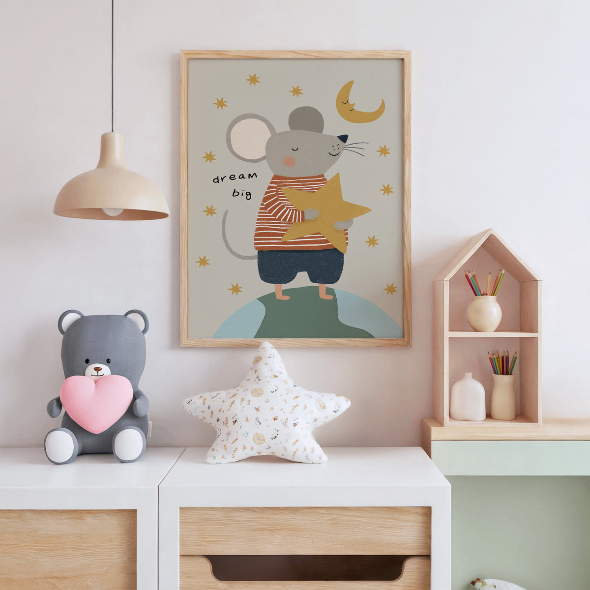 Dream big mouse hugging star nursery print in an oak frame above a white dresser with a star pillow and house shelf