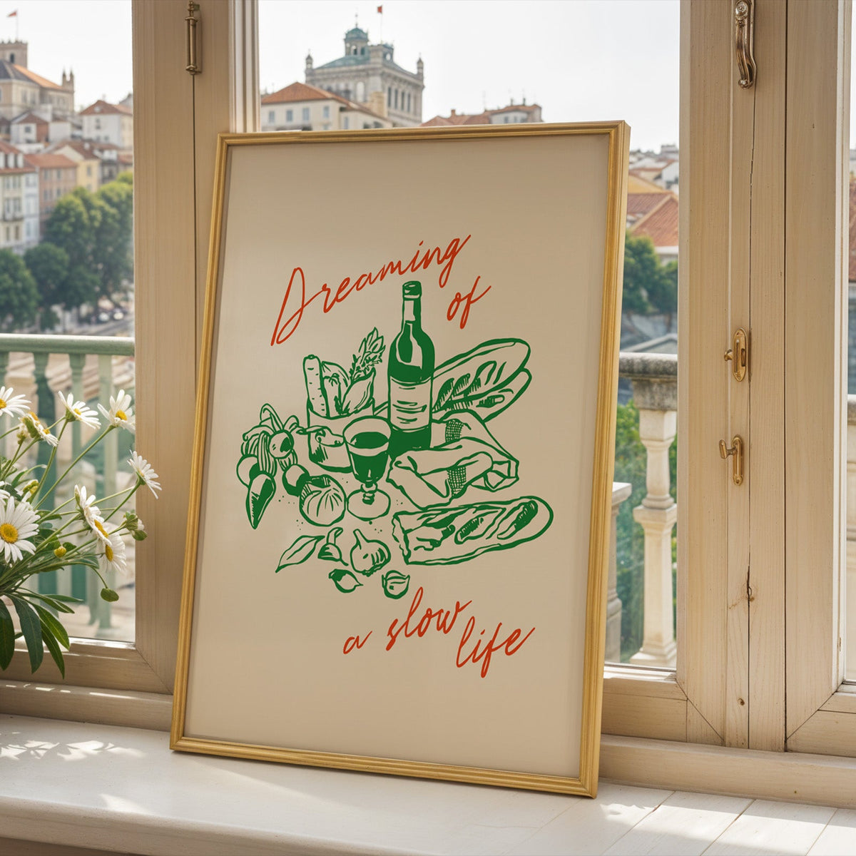 Dreaming of a Slow Life print in a gold frame on a window sill above a hillside town
