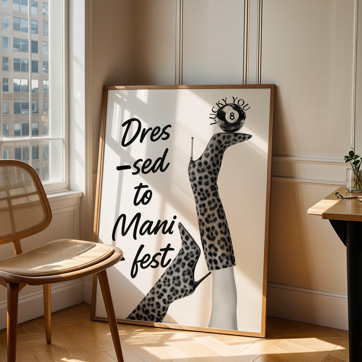 Legs in leopard boots balancing eight ball quote print in an oak frame leaning in a sunlit corner beside a cane chair