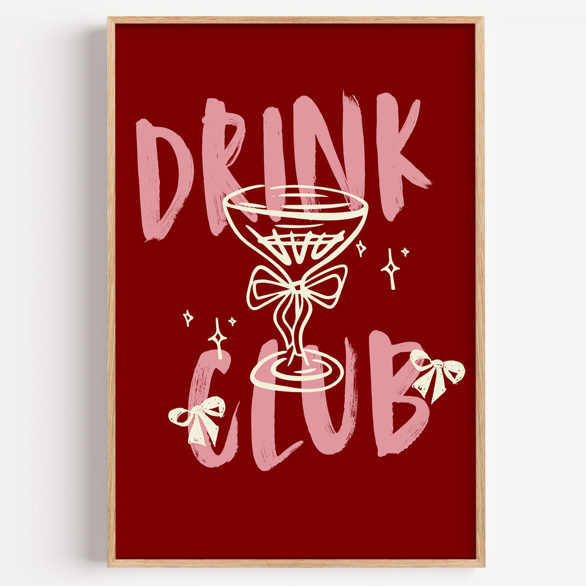 Drink Club dark red coupe glass print in a light oak frame on a plain white wall