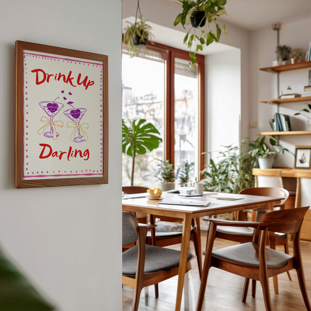 Drink Up Darling print in a walnut frame beside a mid-century dining table