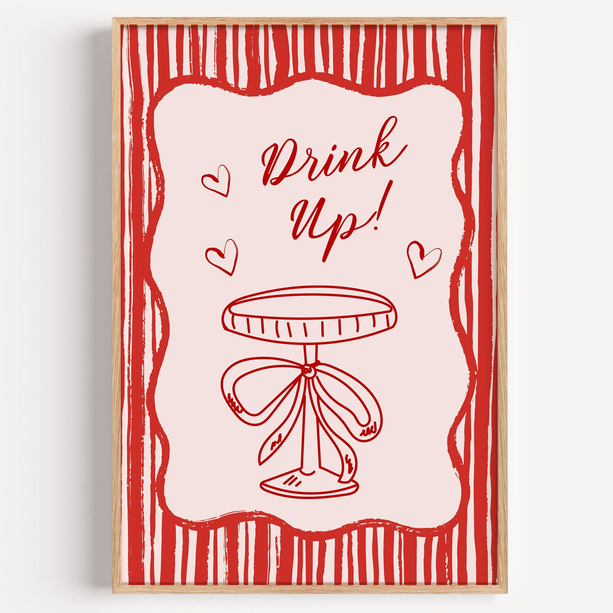 Drink Up red stripe coupe print in a light oak frame on a plain white wall