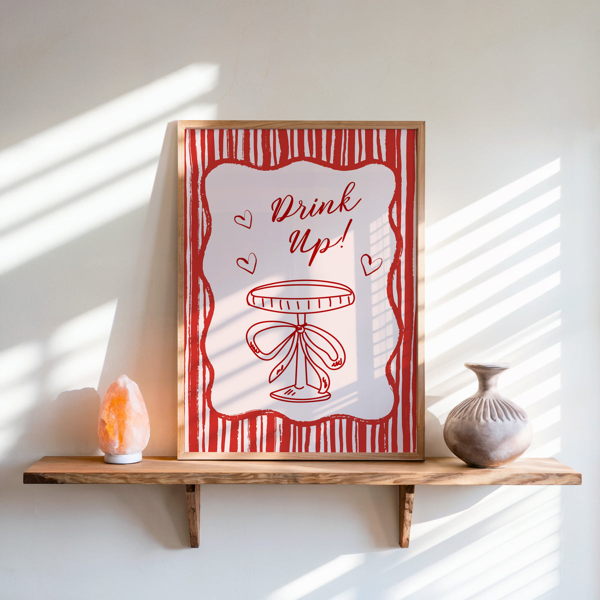 Drink Up coupe print in an oak frame on a live-edge shelf beside a salt lamp