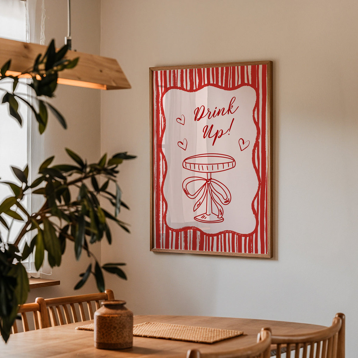 Drink Up coupe print in a walnut frame above a dining table with olive branches