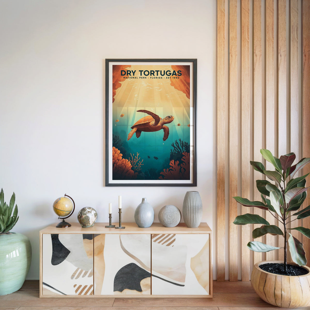 Dry Tortugas National Park print in a black frame above a light wood sideboard with a globe