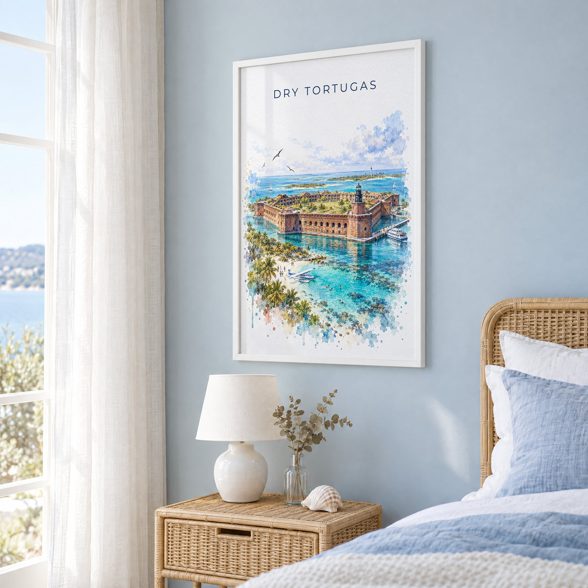 Dry Tortugas National Park watercolor print in a white frame on a pale blue wall beside a rattan bed in a coastal bedroom