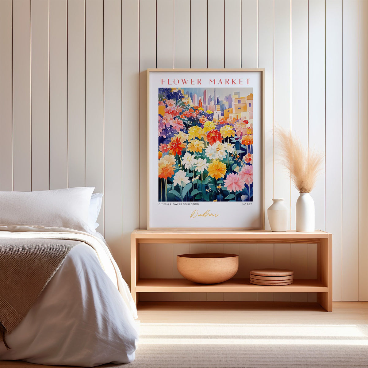 Dubai flower market print in an oak frame on a wood bench against a white shiplap bedroom wall with pampas grass