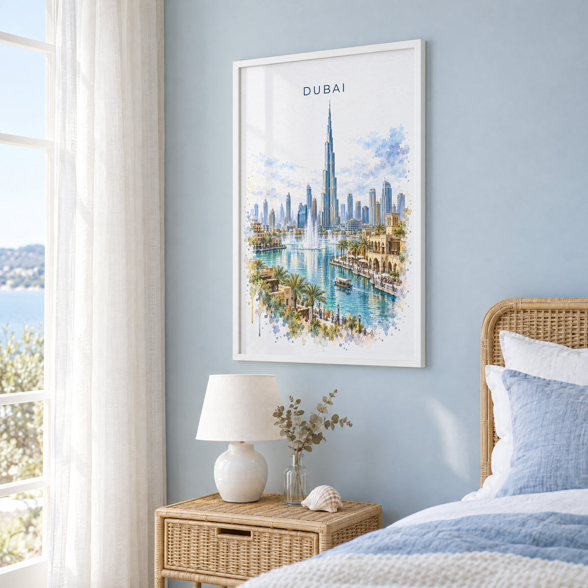 Dubai watercolor print in a white frame on a pale blue wall beside a rattan bed in a coastal bedroom