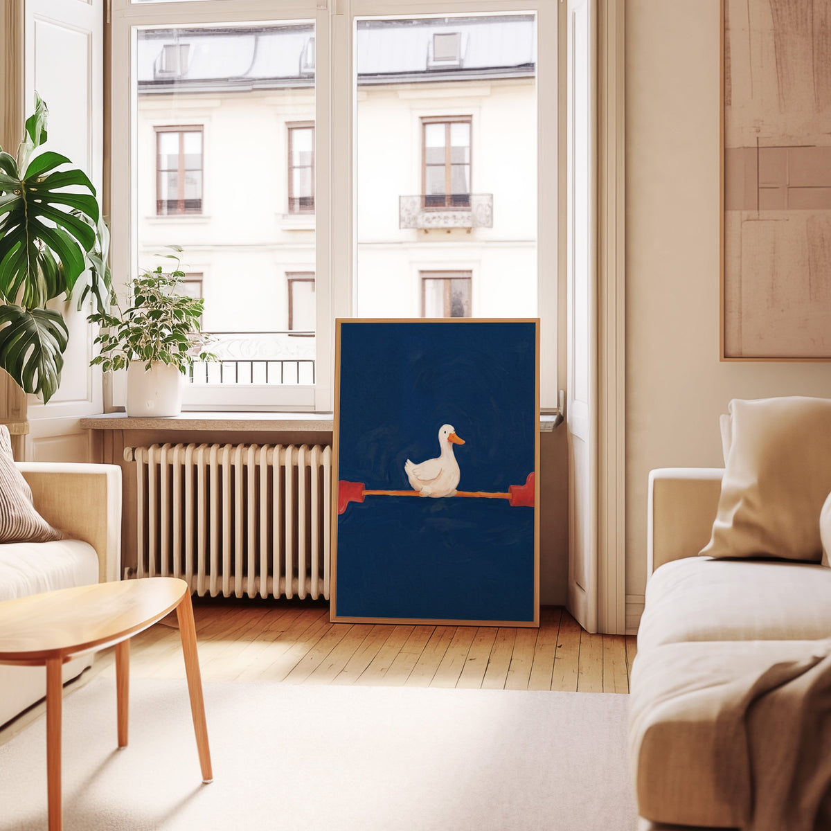 Navy duck wall art print in an oak frame leaning below tall French windows