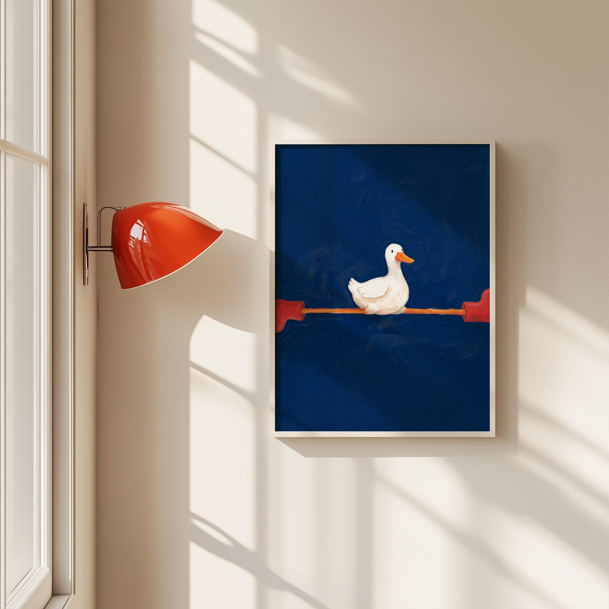 Duck doing the splits print in a white frame beside a red wall sconce