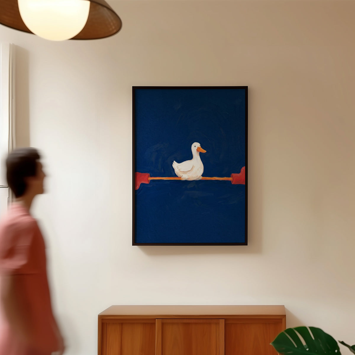 Duck with long legs print in a black frame in a hallway under a rattan pendant