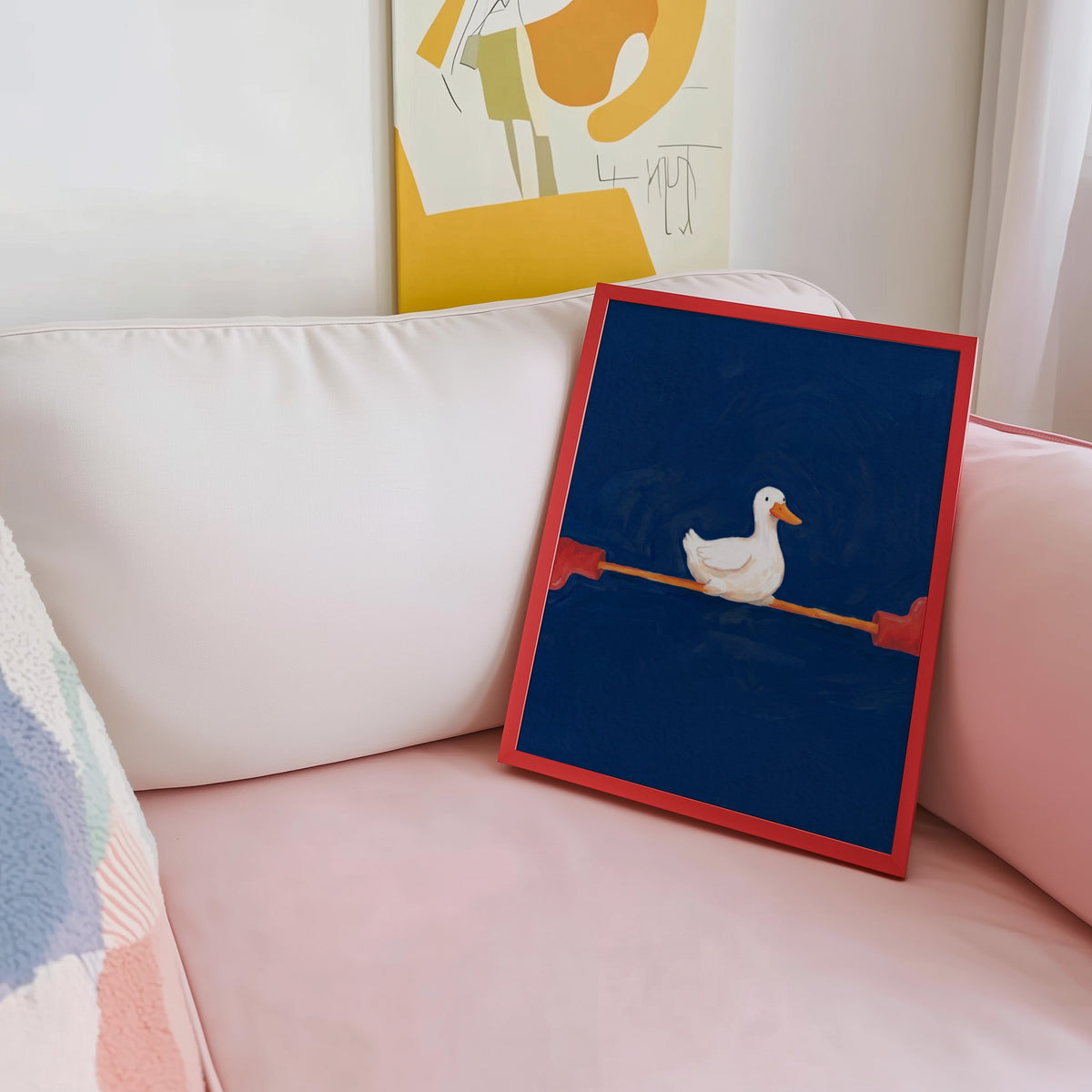 Yoga duck print shown in a red frame leaning on a blush pink sofa
