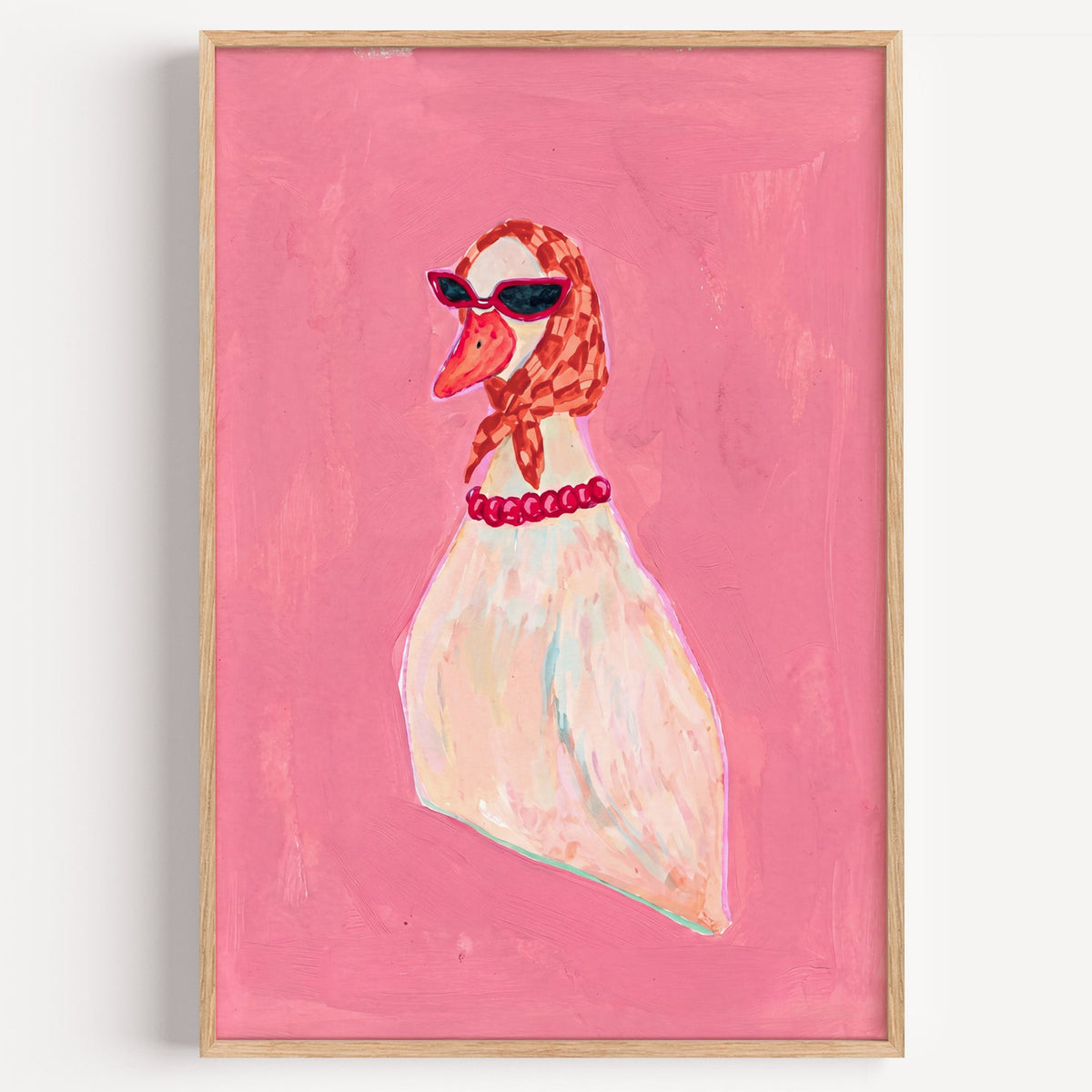 Duck in headscarf and sunglasses print in a light oak frame on a plain white wall