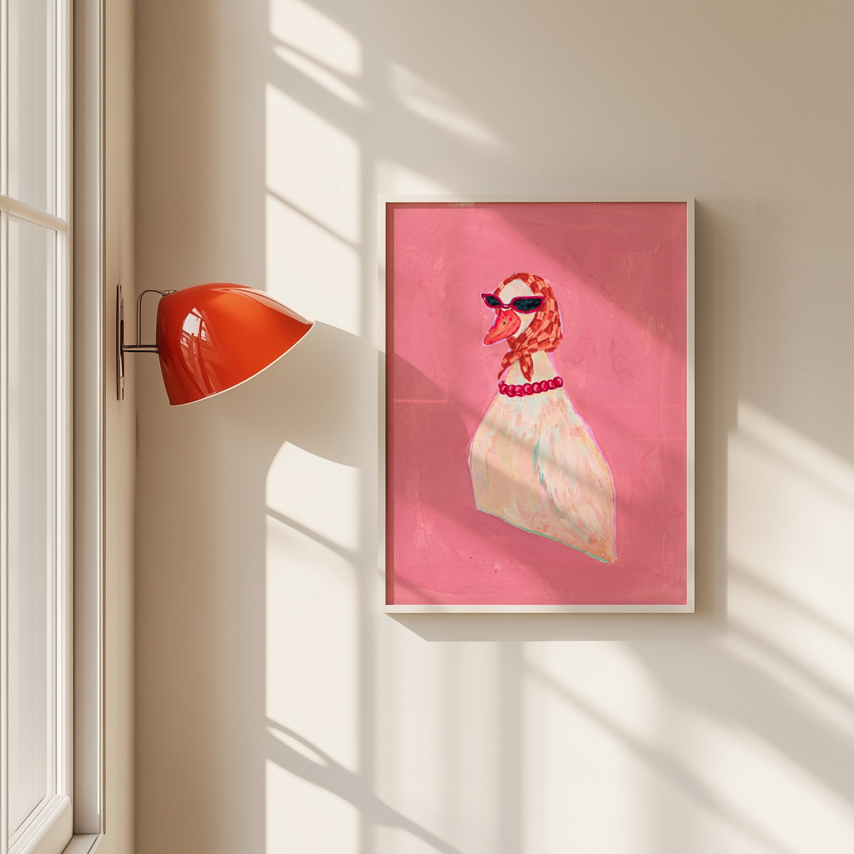 Duck in headscarf and sunglasses print in a white frame beside a red wall sconce