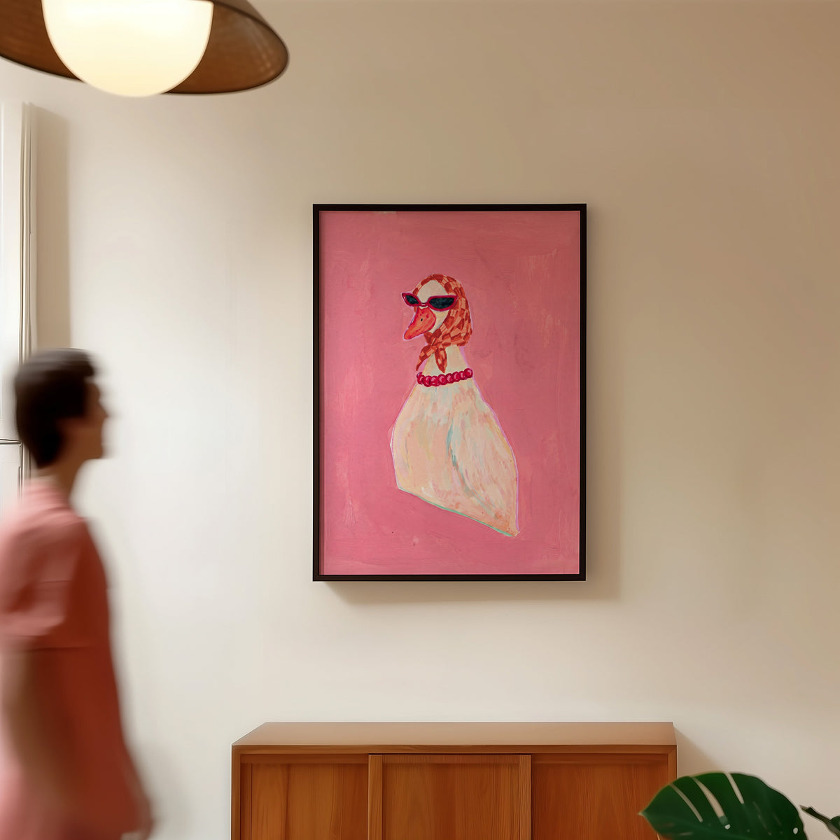 Pink duck fashion print in a black frame in a hallway under a rattan pendant