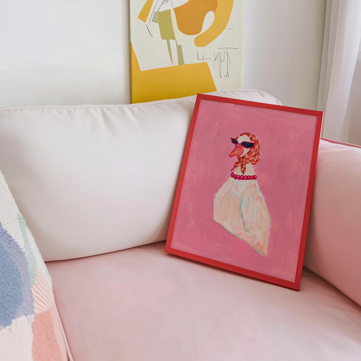 Duck with cat-eye sunglasses print shown in a red frame leaning on a blush pink sofa