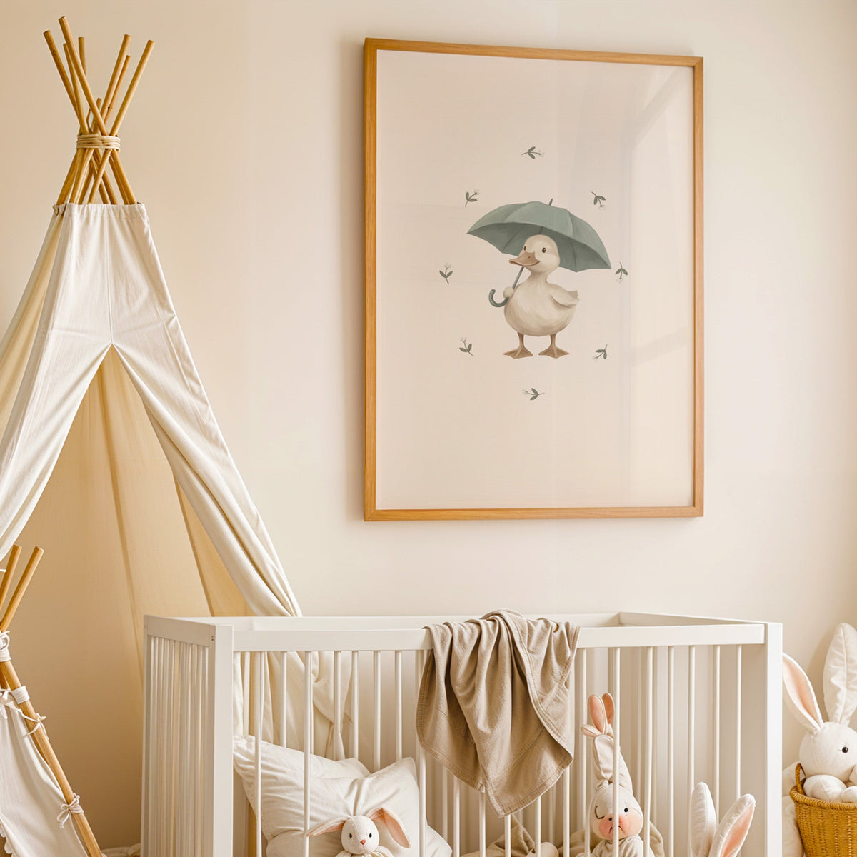 Cream duck holding a sage umbrella nursery print in an oak frame above a white crib beside a canvas teepee