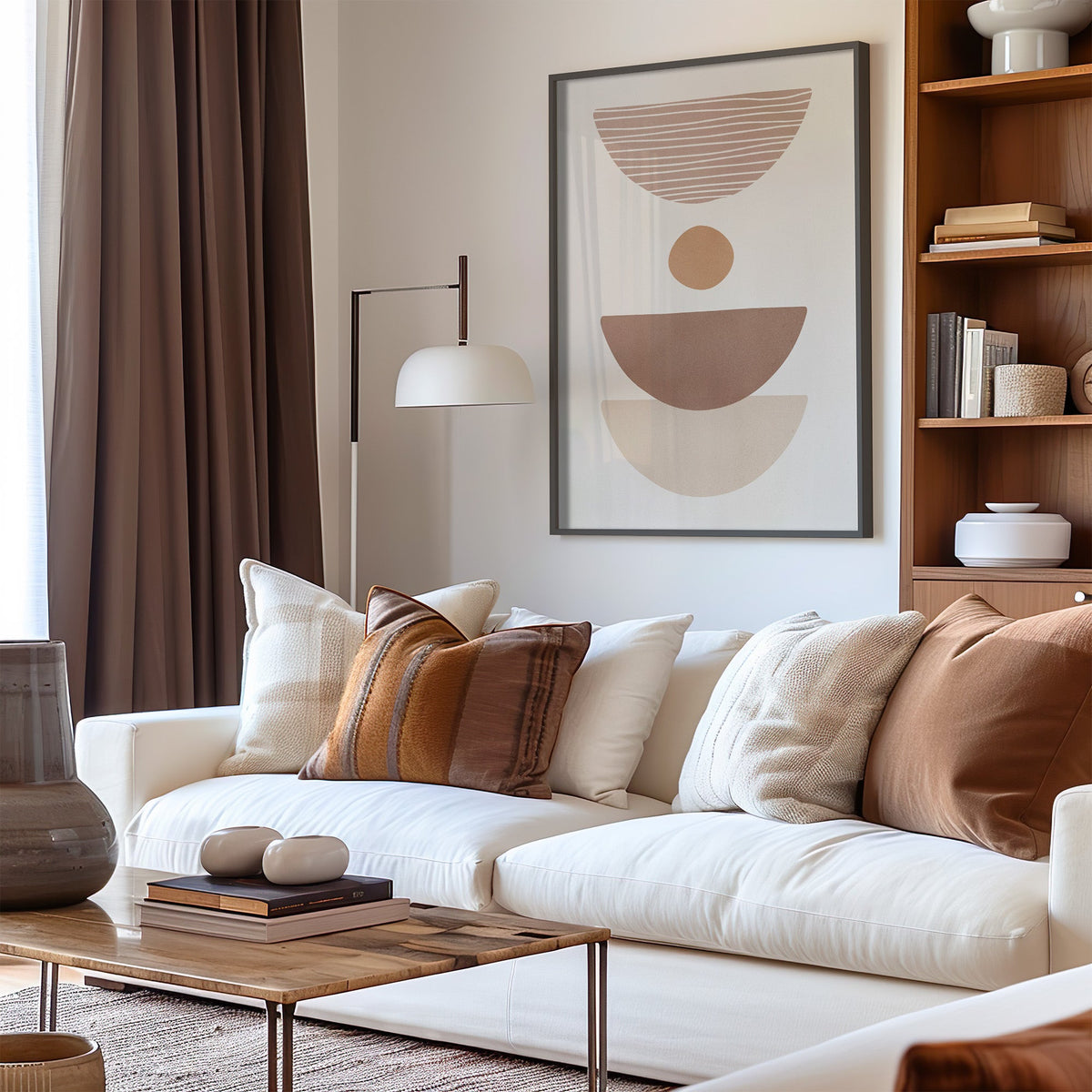 Dusty rose striped bowl shapes boho print in a black frame above a cream sofa with brown striped pillows