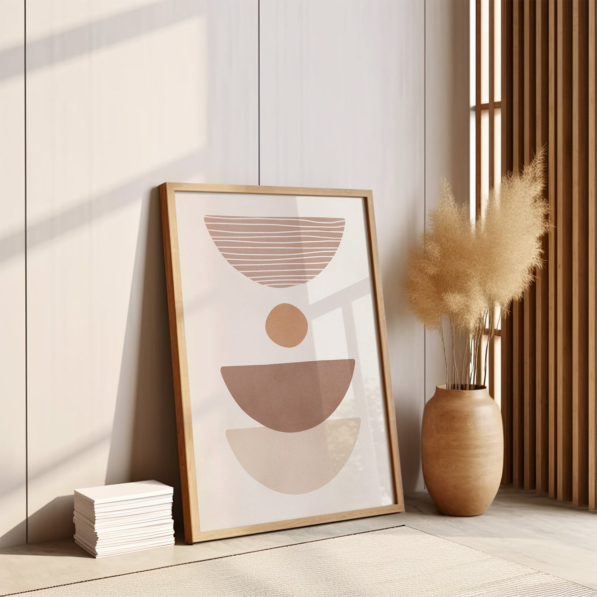 Dusty rose striped bowl shapes boho print in an oak frame leaning on the floor by pampas grass and a wood slat screen