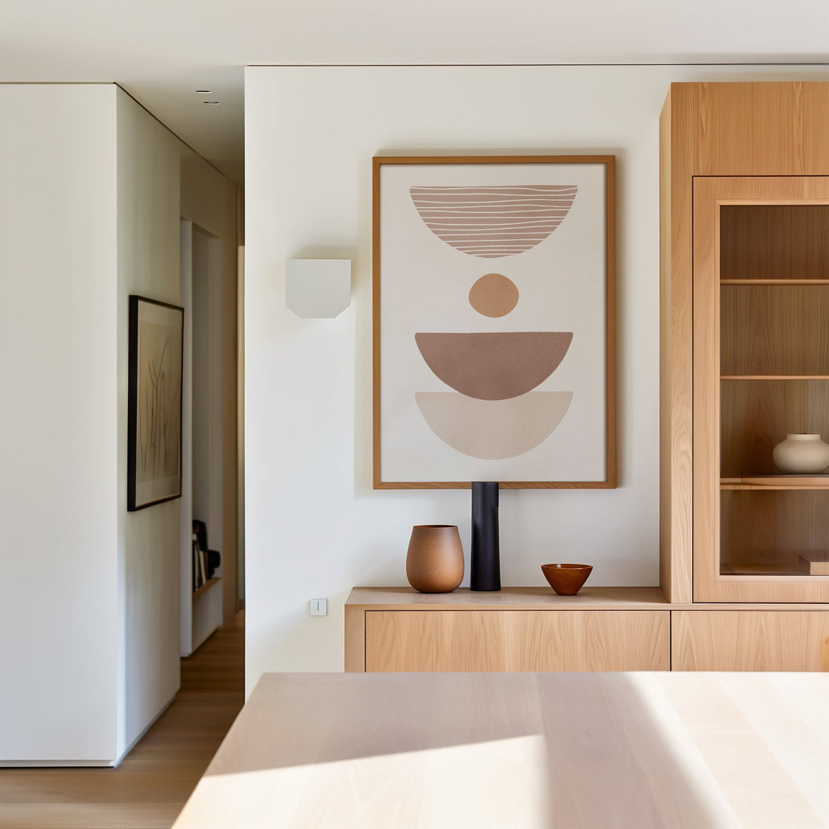 Dusty rose striped bowl shapes boho print in an oak frame above a light oak sideboard in a dining room
