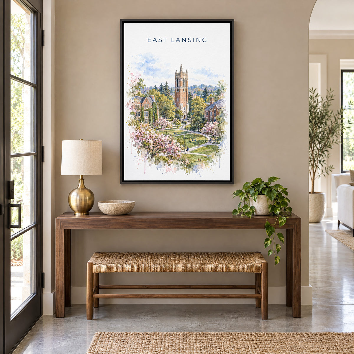 East Lansing watercolor print as a black floater canvas above a walnut console and woven bench in an entryway
