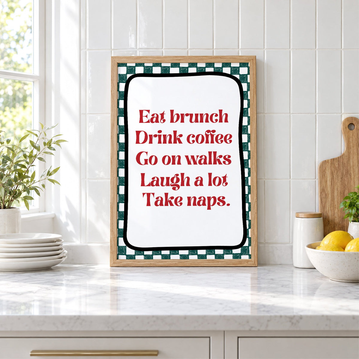 Eat brunch drink coffee check print in an oak frame leaning on a marble counter by white tiles and lemons