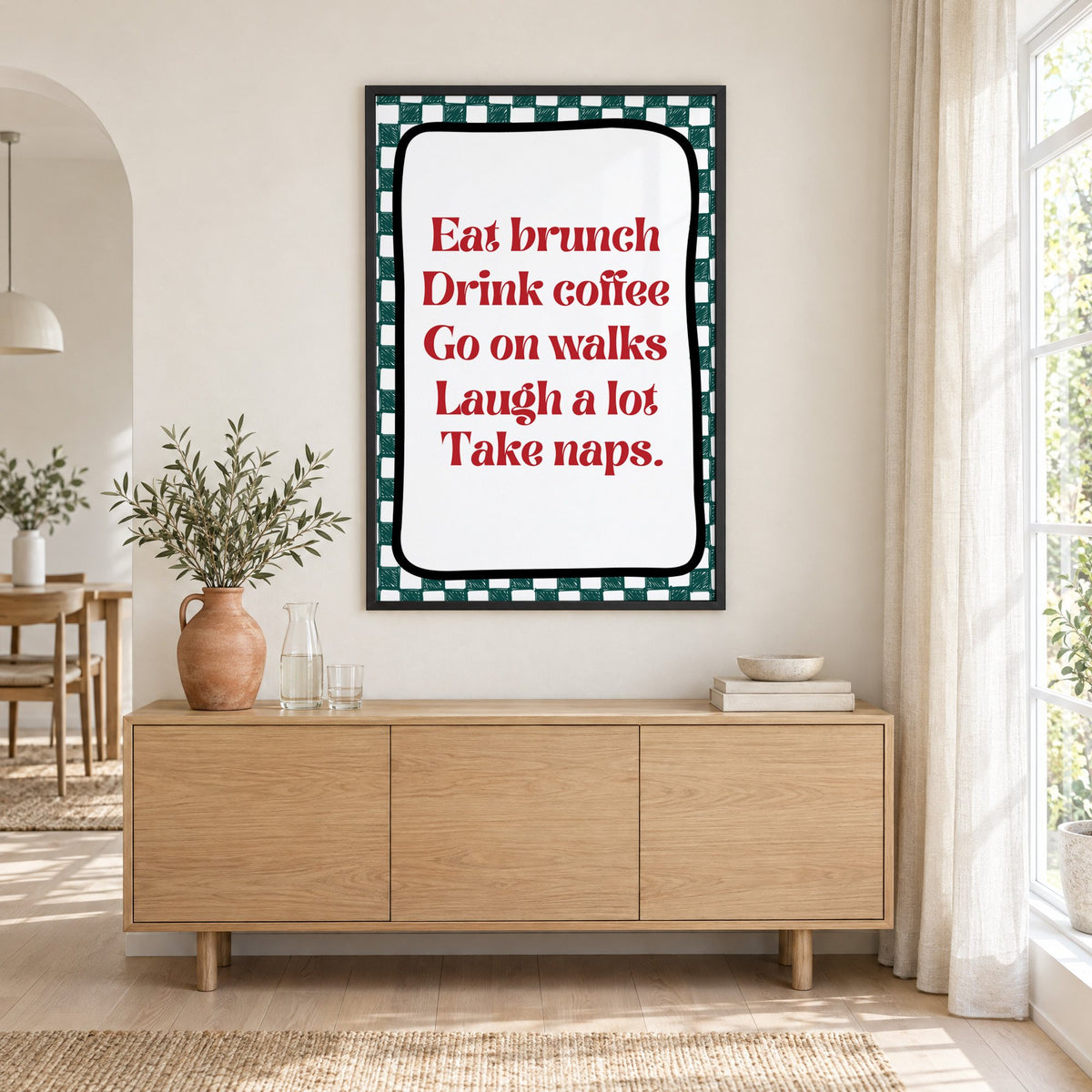Eat brunch drink coffee check print in a black frame above an oak sideboard with a terracotta vase of olive branches