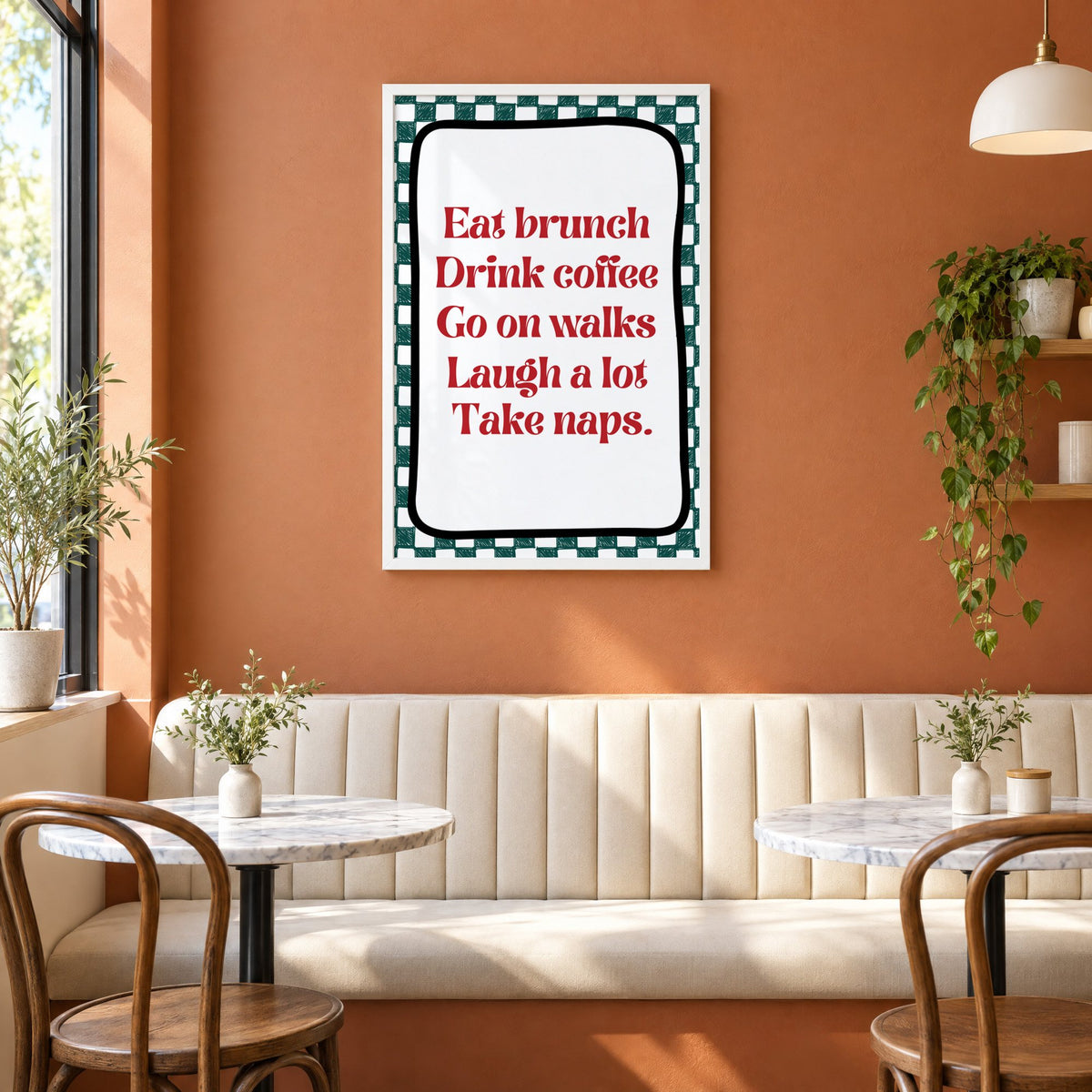 Eat brunch drink coffee check print in a white frame above a cream banquette on a terracotta cafe wall