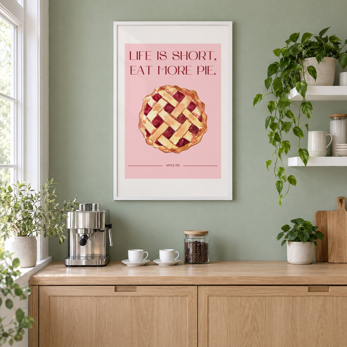 Eat More Pie watercolor print in a white frame on a sage green coffee nook wall above an espresso machine