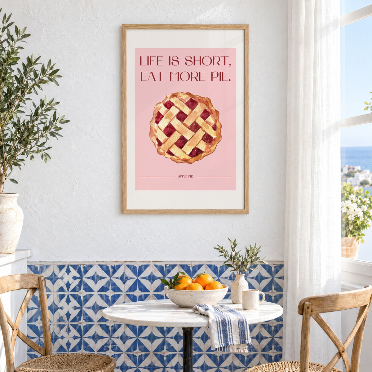 Eat More Pie watercolor print in an oak frame above a bistro table and blue patterned tiles