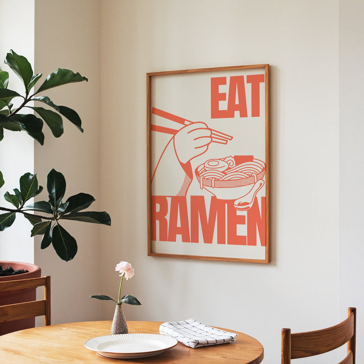 Eat Ramen print in a walnut frame above a round table beside a fiddle-leaf fig