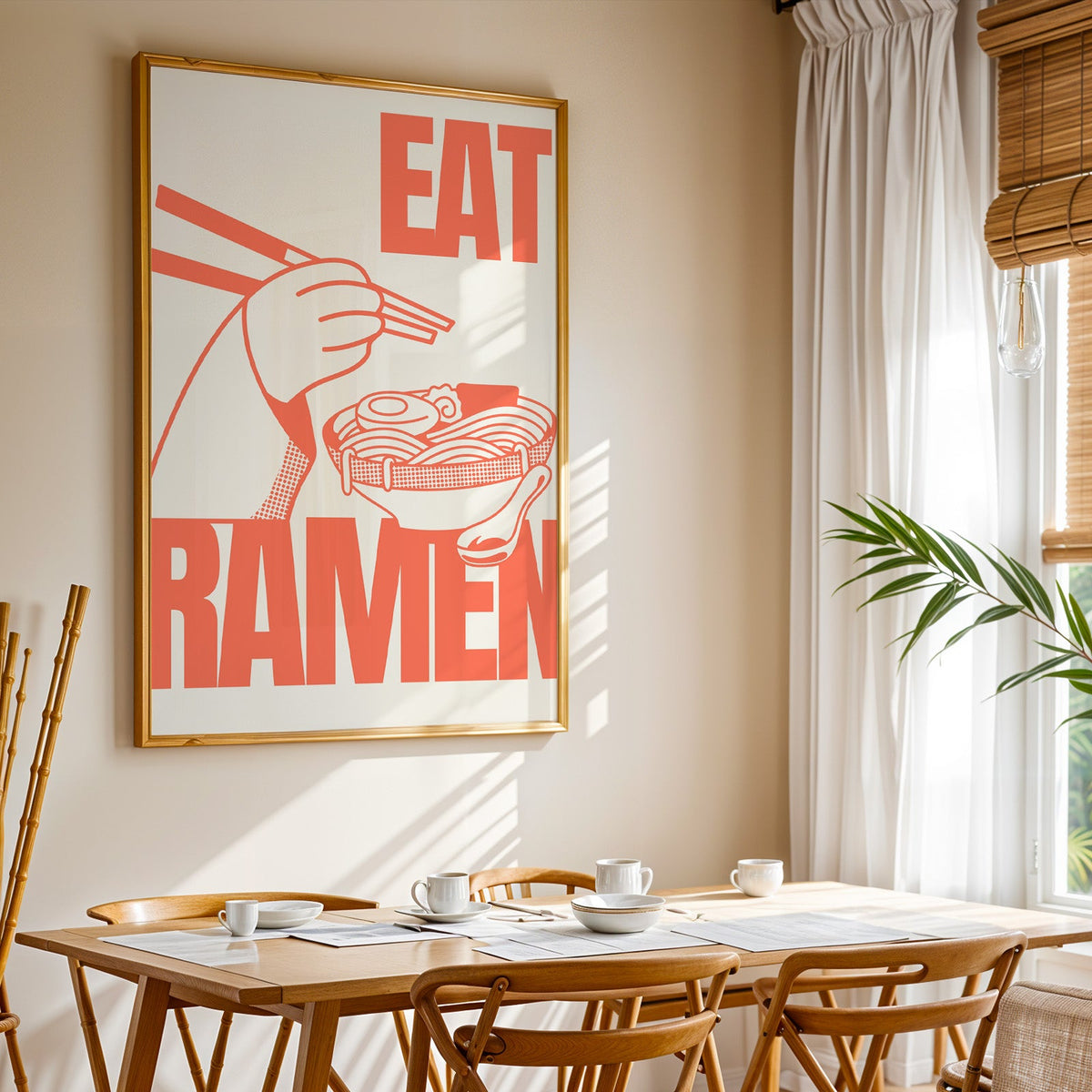 Eat Ramen print shown in a gold frame above a breakfast table by a curtained window