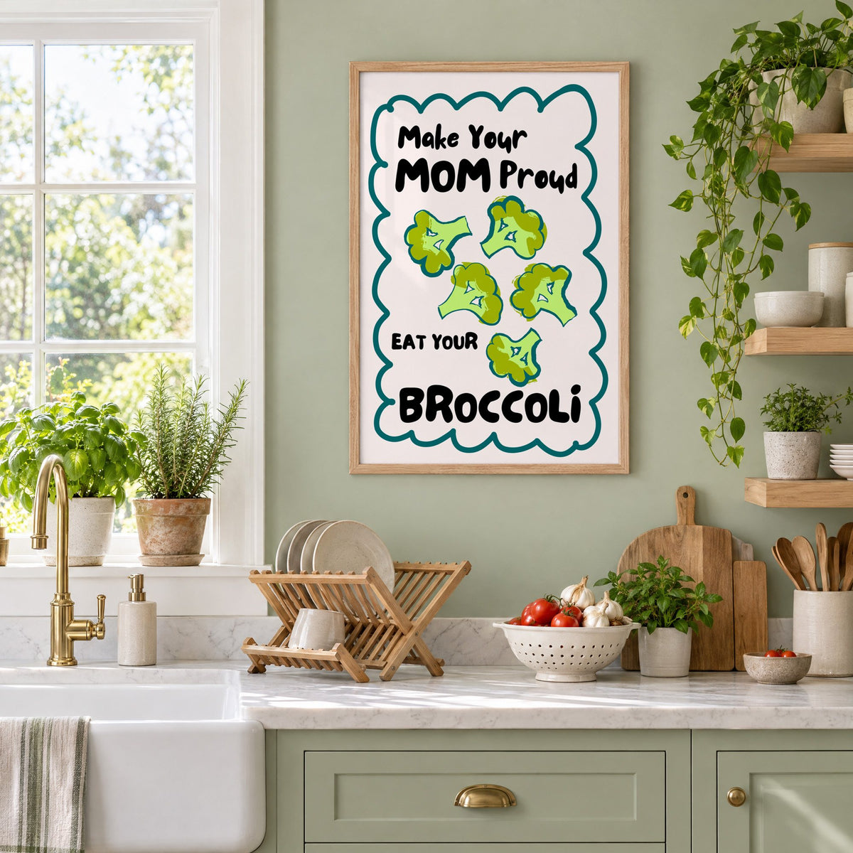 Eat Your Broccoli pink kitchen print in an oak frame on a sage green kitchen wall beside a farmhouse sink and herbs