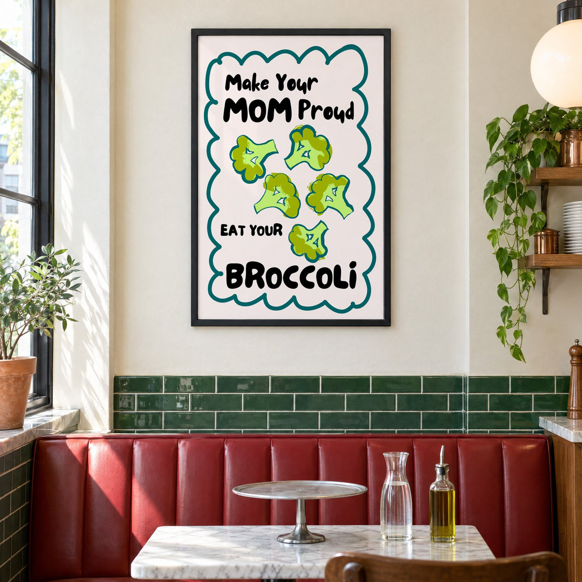 Eat Your Broccoli pink kitchen print in a black frame above a red leather booth in a sunny pizzeria
