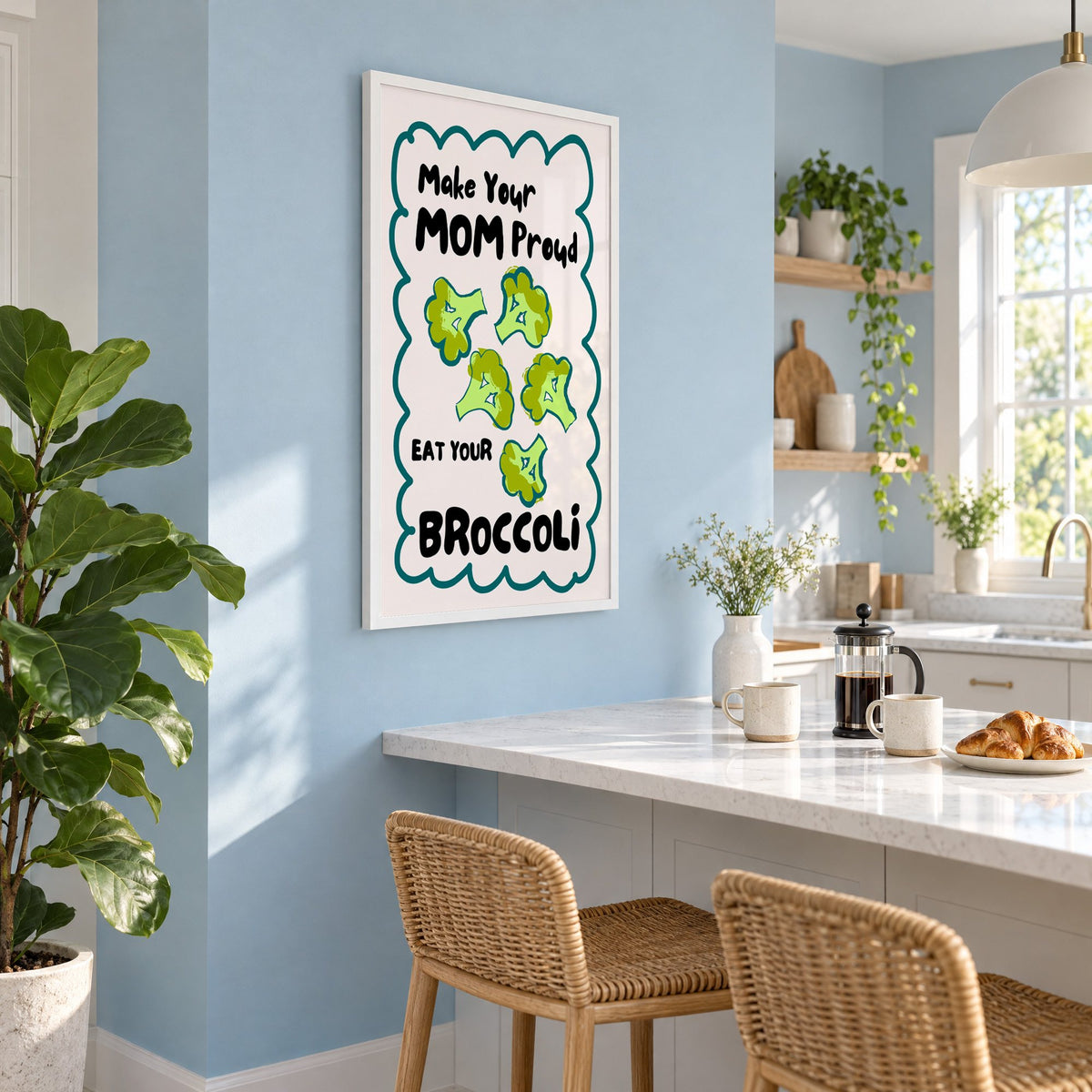 Eat Your Broccoli pink kitchen print in a white frame on a pale blue wall above a breakfast bar with rattan stools
