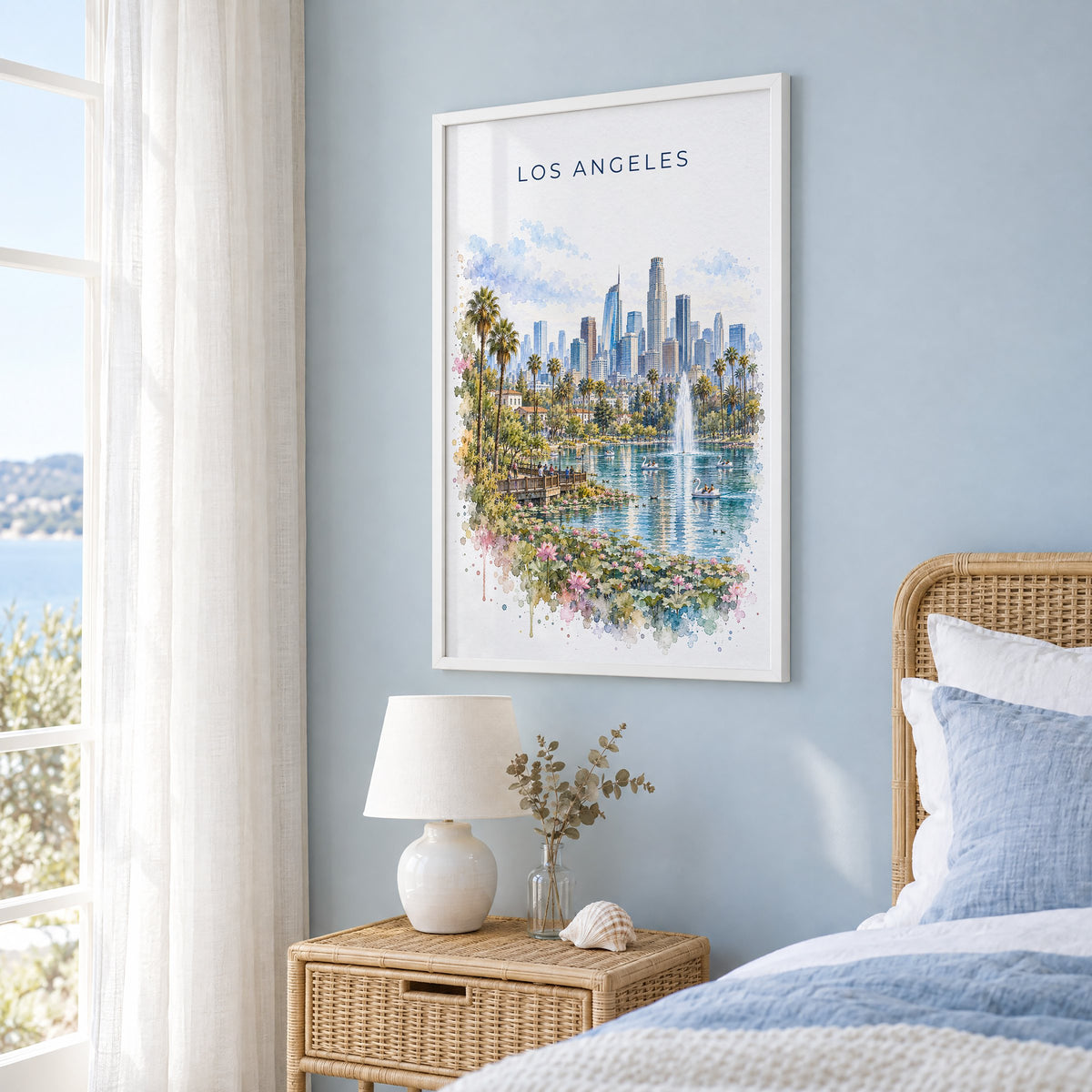 Echo Park Los Angeles watercolor print in a white frame on a pale blue wall beside a rattan bed in a coastal bedroom