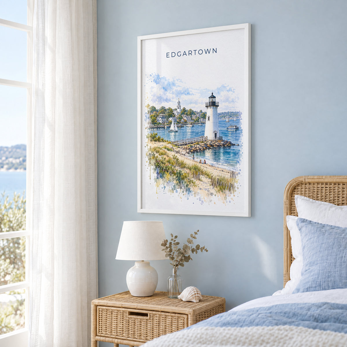 Edgartown watercolor print in a white frame on a pale blue wall beside a rattan bed in a coastal bedroom