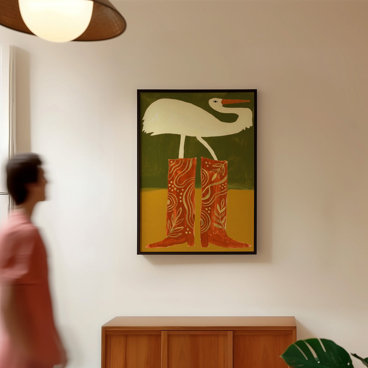 Bird wearing cowboy boots print in a black frame in a hallway under a rattan pendant